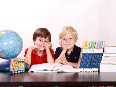 to drenge som sidder ved et bord blandt en globus og bøger